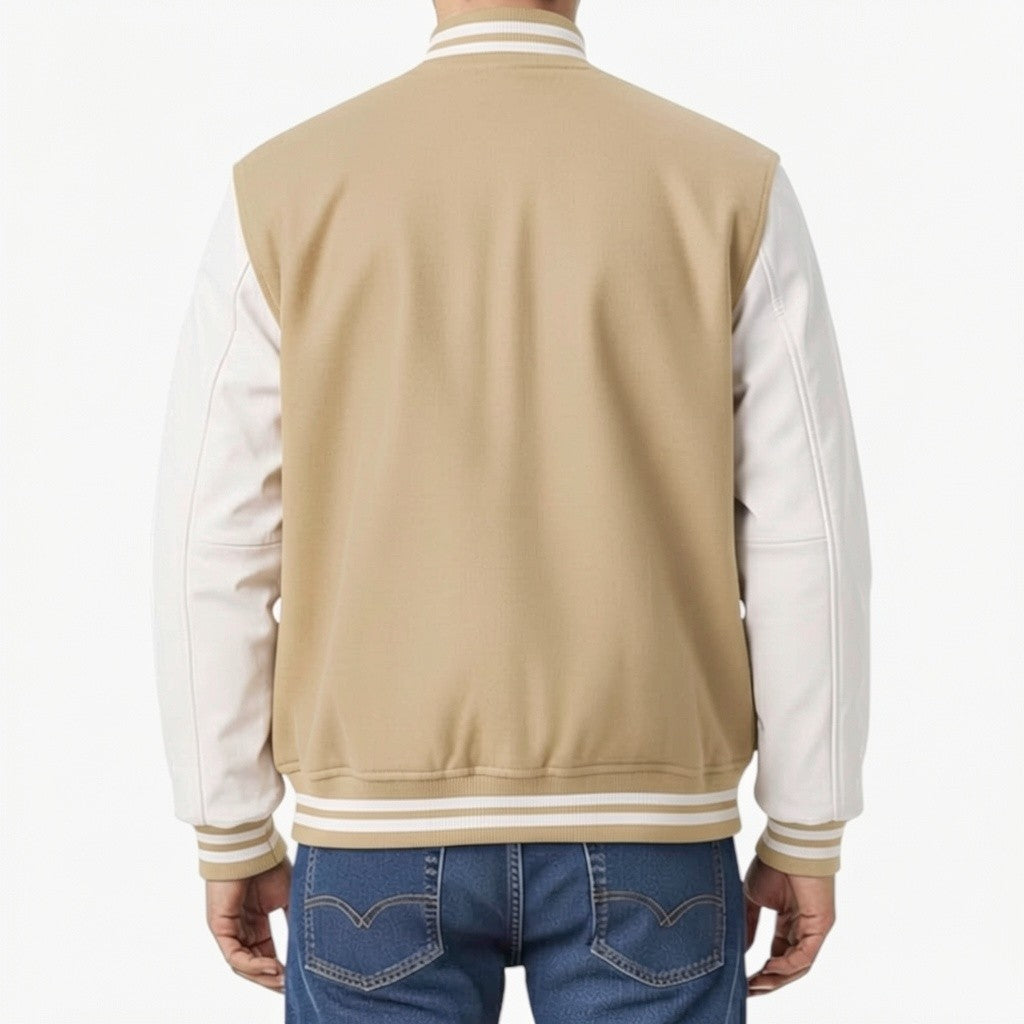 Person wearing a beige and white varsity jacket with blue jeans on a white background