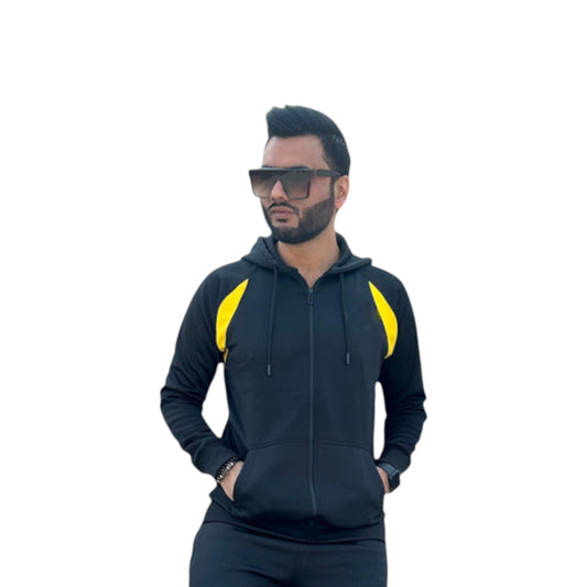 A male model wearing a black and yellow cropped track suit jacket with a hood, paired with matching pants.