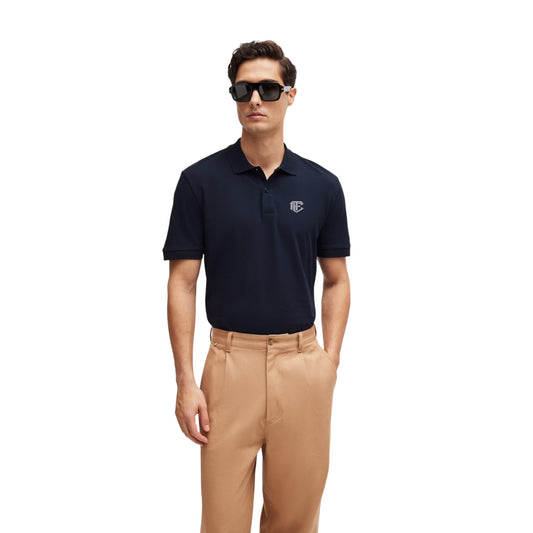 A man wearing a navy blue regular-fit polo shirt with a logo on the chest and light brown chinos.