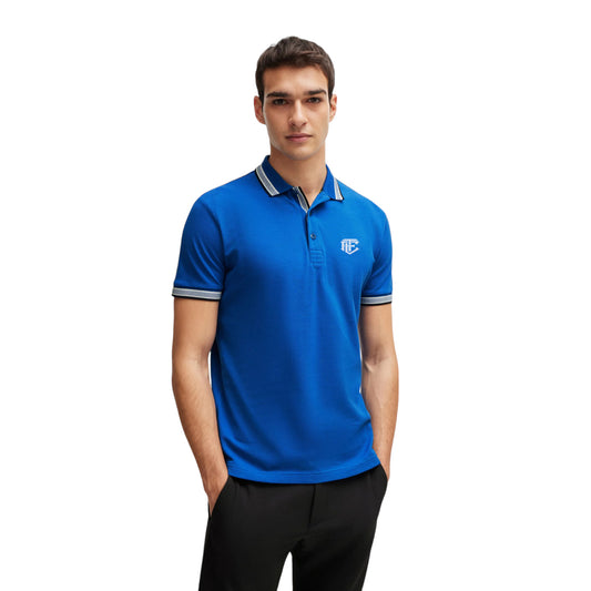 A man wearing a blue, short-sleeved, collarless polo shirt with a logo on the chest.