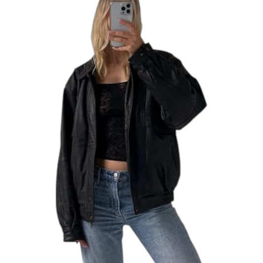 A woman wearing a black oversized leather jacket with a hood, paired with a black top and blue jeans.