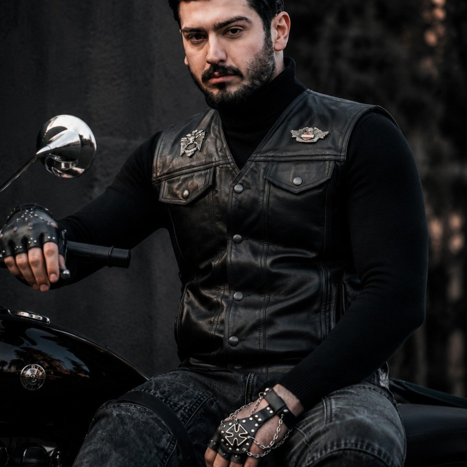 Man wearing genuine leather vest in a rugged outdoor setting, showcasing premium quality biker style.