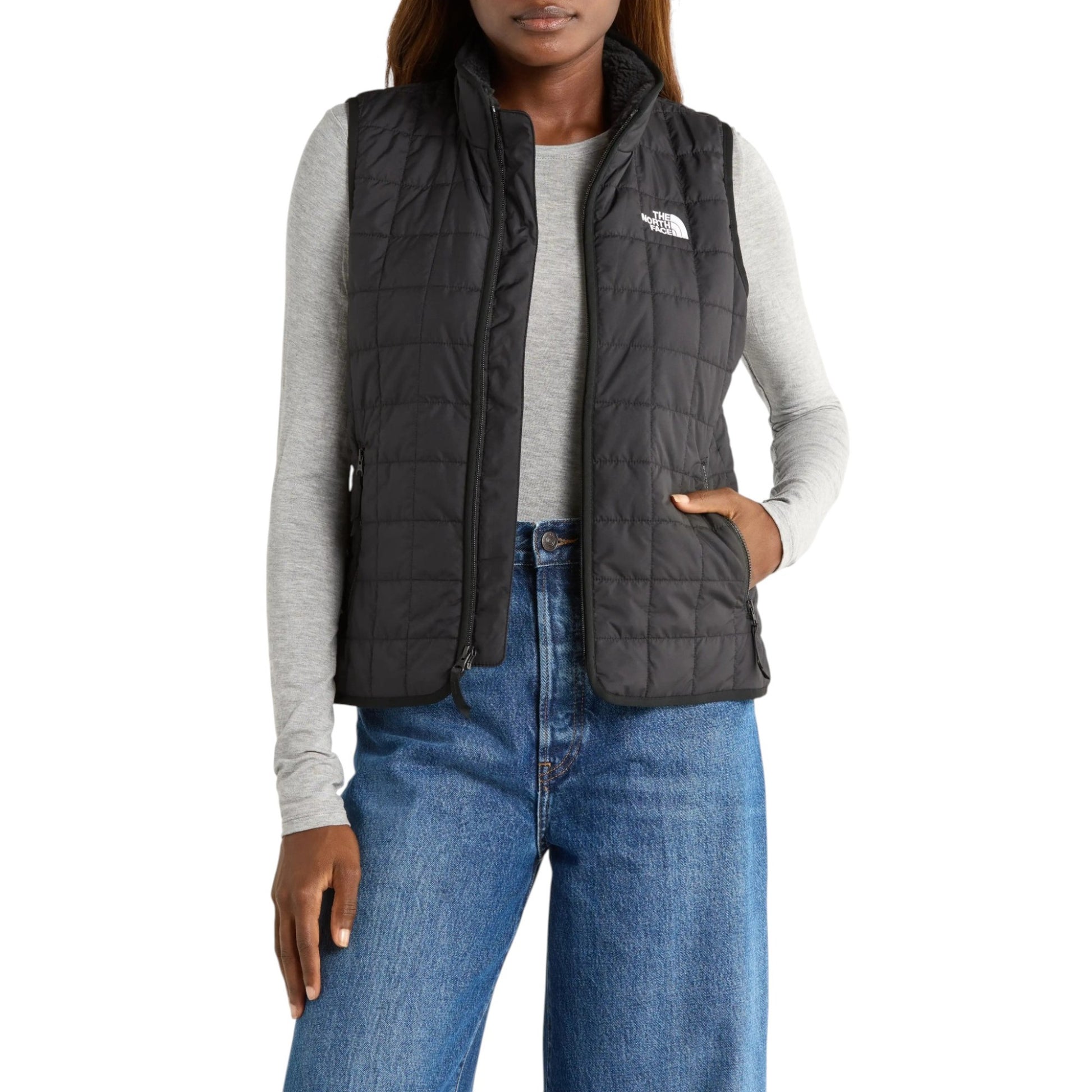 Person wearing a black puffer vest with The North Face logo on a white background