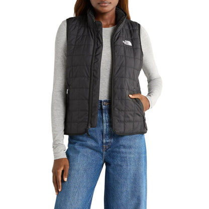 Person wearing a black puffer vest with The North Face logo on a white background