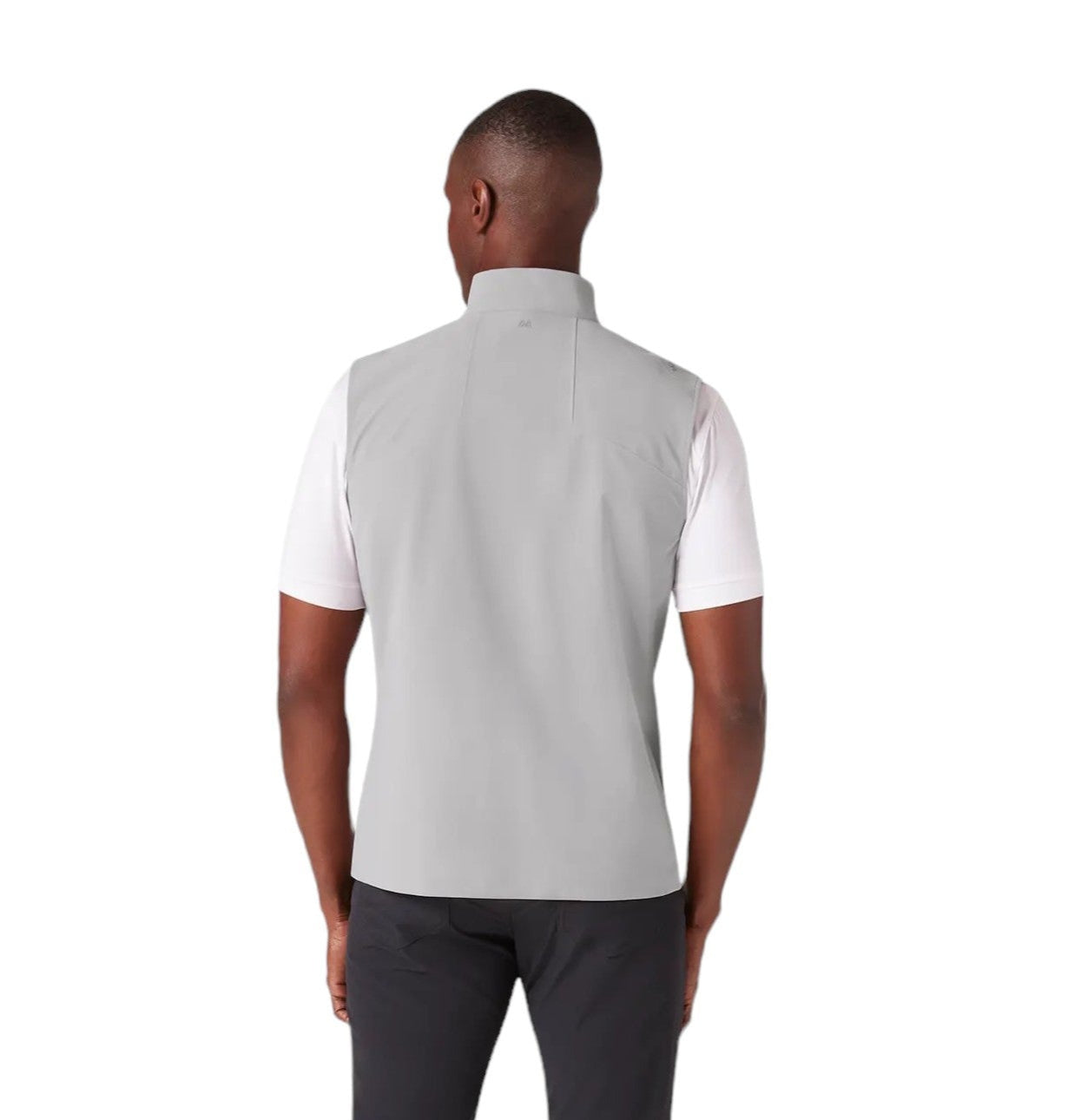 Man wearing a gray vest over a white shirt with dark pants on a white background