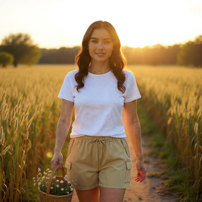 Woman standing in a field holding a basket of flowers during sunset.