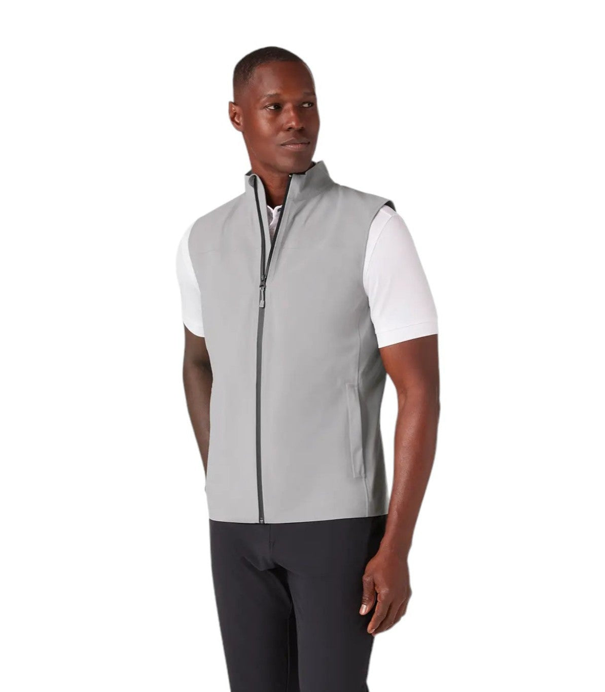Man wearing a gray vest over a white shirt with dark pants on a white background
