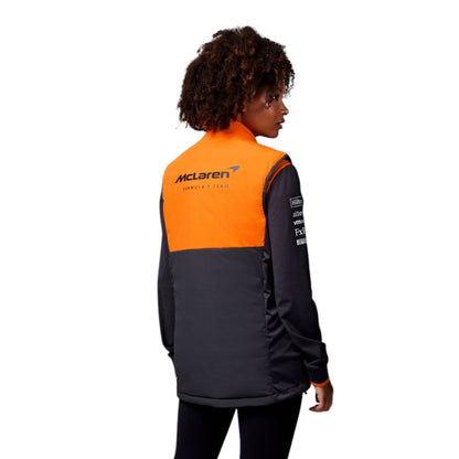 Person wearing a black and orange jacket with McLaren logo on a white background