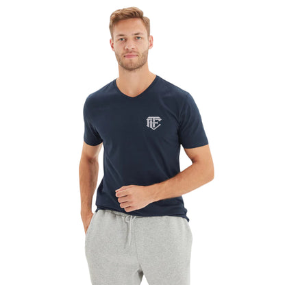 A man wearing a navy blue Henley T-shirt with a collar and front button closure, paired with grey sweatpants.