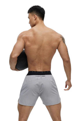 Man wearing gray athletic shorts with a black waistband on a white background