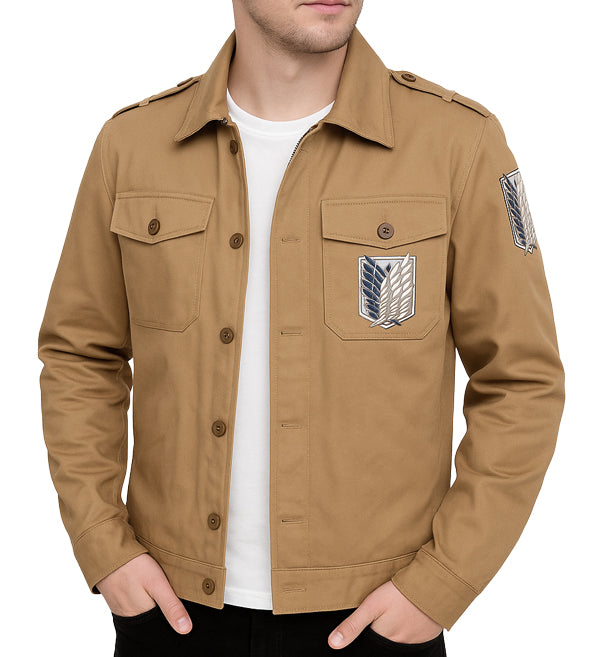 A man wearing a tan military-style field jacket with Attack on Titan insignia patches on the chest and sleeve, layered over a white t-shirt.