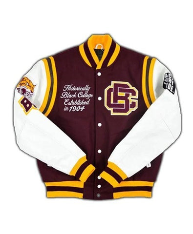 A varsity-style letter jacket with a maroon body, white sleeves, and yellow/gold stripes and trim. The front has a button closure, embroidered script reading 'Historically Black College Established in 1907,' a large 'UC' monogram, and a tiger patch on the left sleeve.