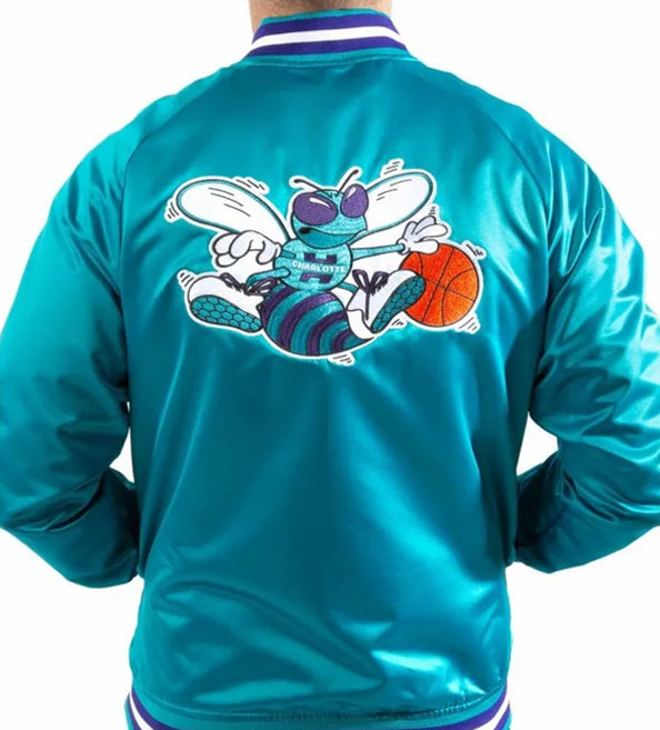 A person shown from the back wearing a shiny teal satin-style jacket with a large cartoon bee graphic on the back and a basketball near the wing. The jacket has a white, purple, and teal striped collar and hem.