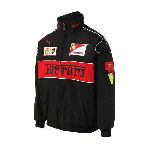 A black Ferrari F1 team zip-up jacket with a bold red chest stripe featuring the 'Ferrari' logo in black. The jacket has white piping details, a Puma logo on the right chest, and various sponsor patches including Shell, Castor, and Cosworth on the left chest and sleeve.