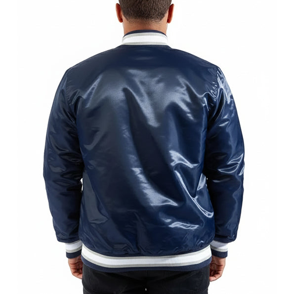 A man viewed from behind wearing a shiny navy blue satin bomber jacket with white ribbed trim at the collar, cuffs, and hem, against a plain white background.