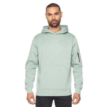 Man wearing a light green hoodie and black pants on a white background
