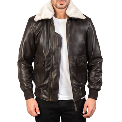 A man wearing a dark brown leather bomber jacket with a white ribbed collar, zipper front, and side pockets, paired with a white t-shirt and black pants.
