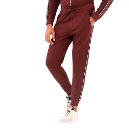 A man wearing maroon office trousers with a mid-rise waistband, side and rear pockets, and white sneakers.