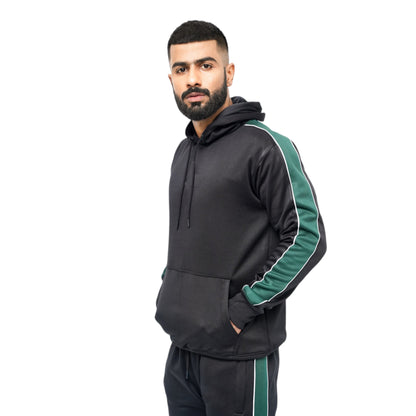 A male model wearing a black and green performance track suit top with a hood, full-length zip closure, and green side stripes on the sleeves.