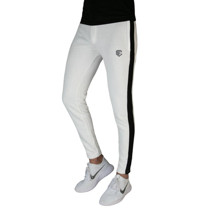 A pair of white athletic pants with black panels on the sides, displayed on a male model wearing white sneakers and a black top.