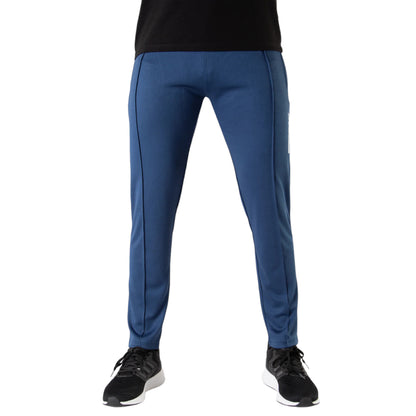 A person standing and facing forward, wearing blue bottoms with black panels, typically referred to as Tech Pants, with a slim fit and full length.