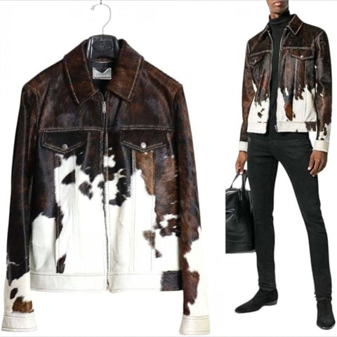 A cow-print leather jacket shown on a hanger on the left and worn by a model on the right. The jacket features a brown and white cowhide pattern with a front zipper, chest pockets, and a collar.