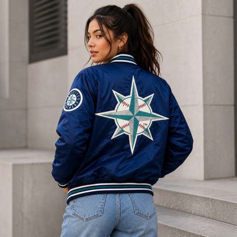 A woman wearing a navy blue satin bomber jacket with a large Seattle Mariners baseball star logo on the back, standing on outdoor concrete steps.