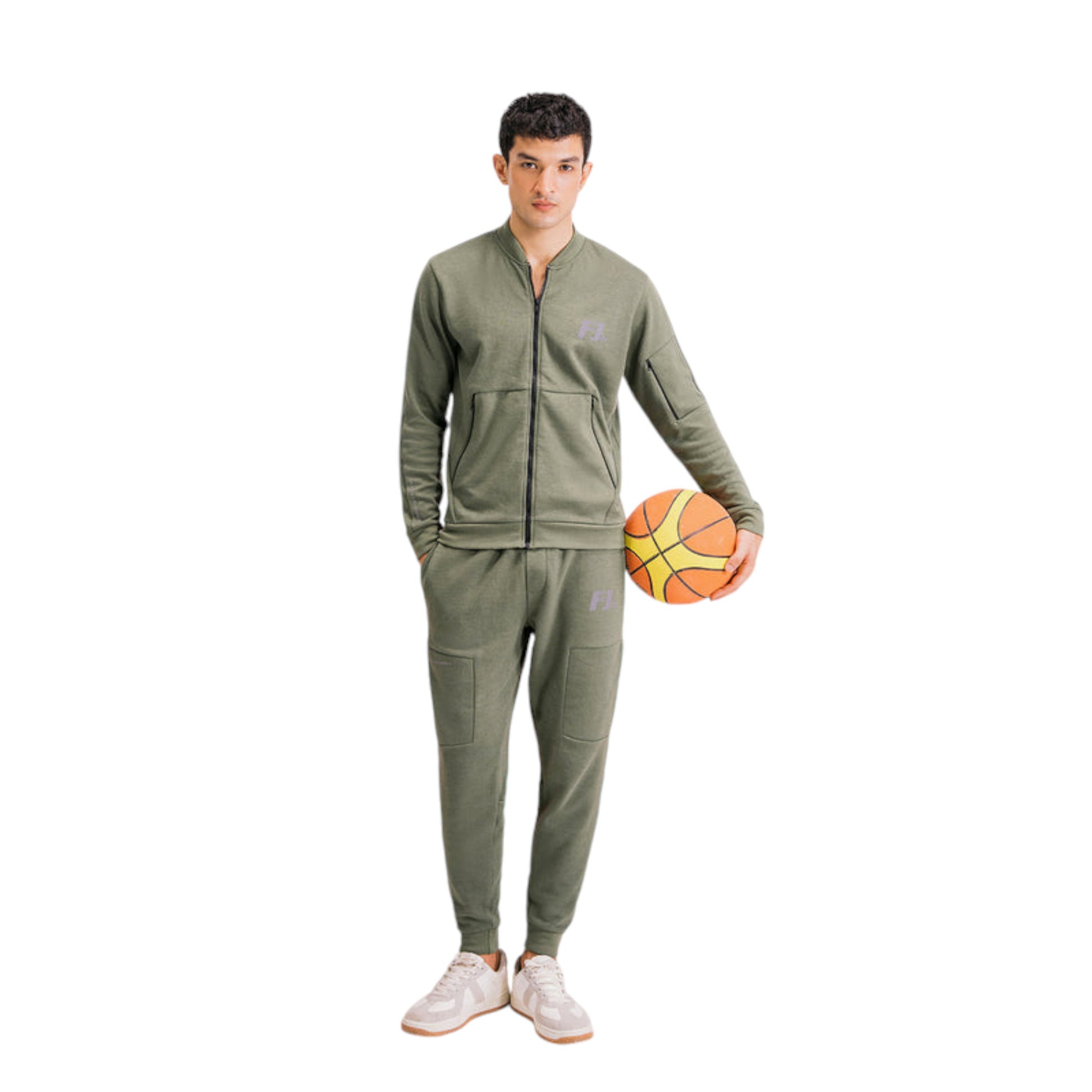 A male model wearing a green full-zip tracksuit holding a basketball.