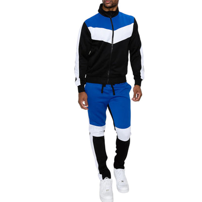 A man wearing a color block track suit with a full zip jacket and matching joggers in blue, black, and white colors.