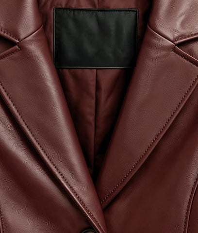 Close-up of a burgundy leather jacket with a black interior label, showing the texture and stitching details.