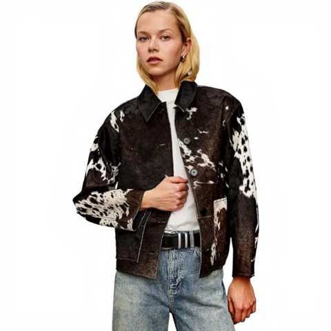 A woman modeling a black and white cow-print fringed jacket with a black cowboy hat, shown against a plain white background.