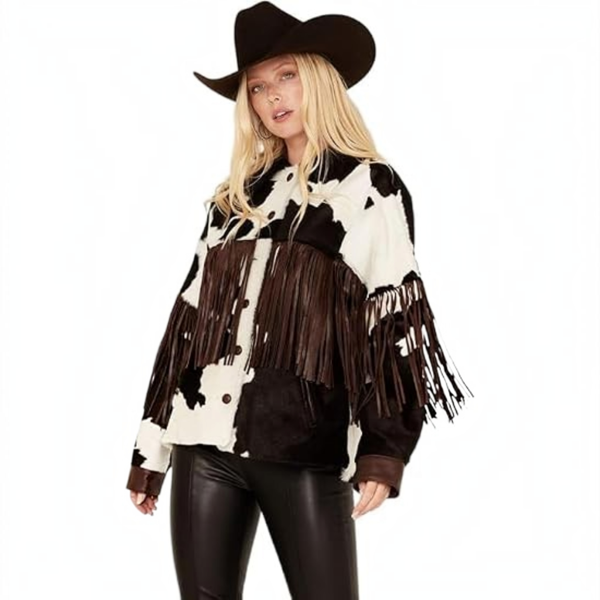 A woman modeling a black and white cow-print fringed jacket with a black cowboy hat and black faux-leather pants, set against a plain white background.