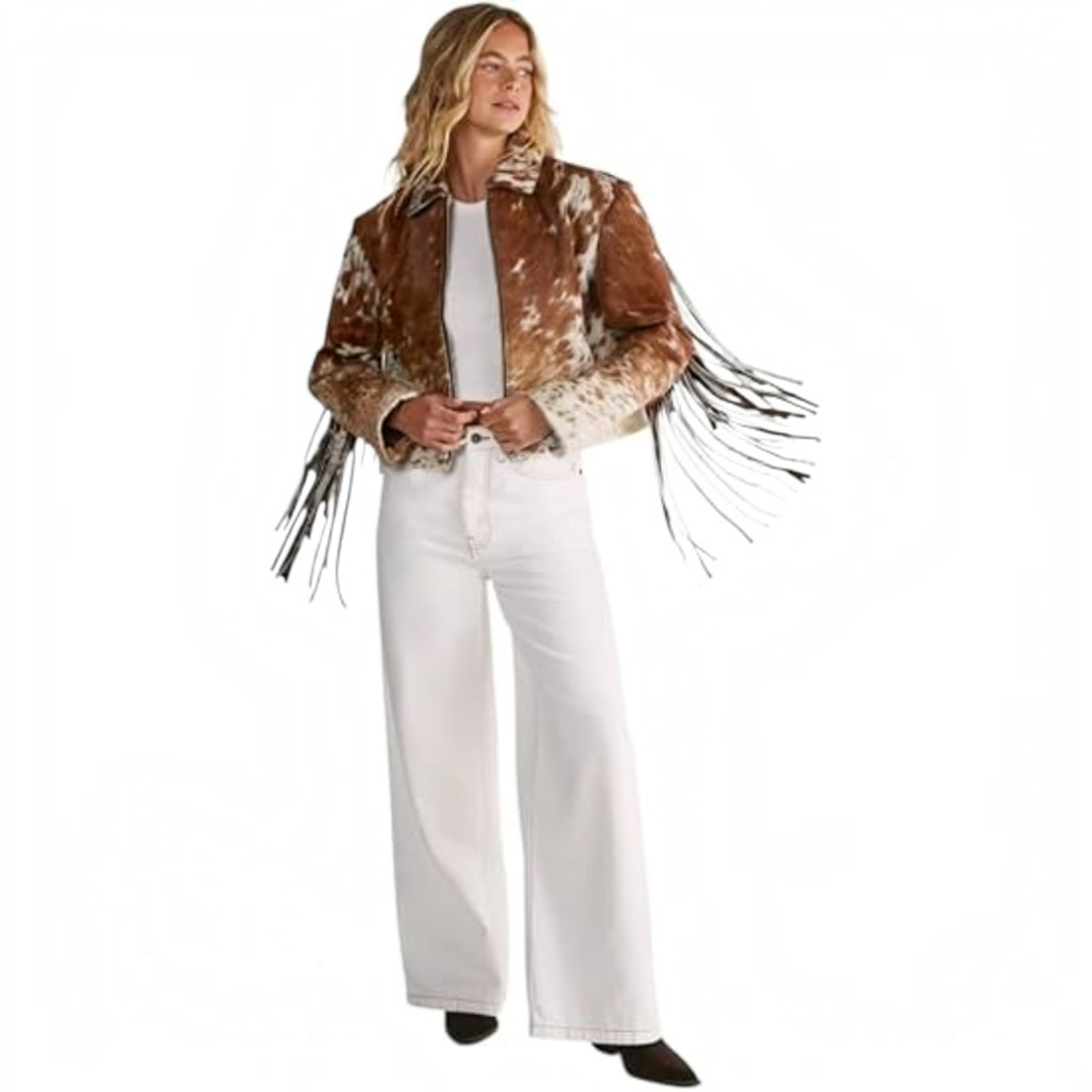 A woman modeling a brown and white cow-print fringed jacket over a white top and white wide-leg jeans, standing against a plain white background.