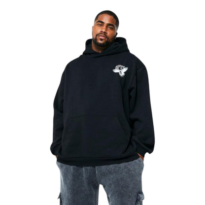 A person wearing a black hoodie with a front kangaroo pocket and a small graphic logo on the upper left side, paired with gray pants.